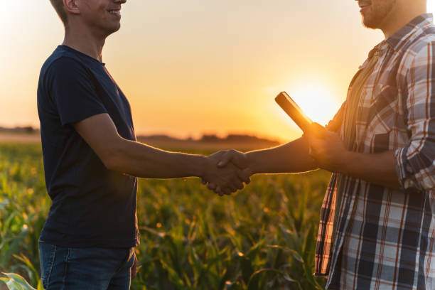 istock Male farmer and agronomist shaking hands in corn field 1451087006