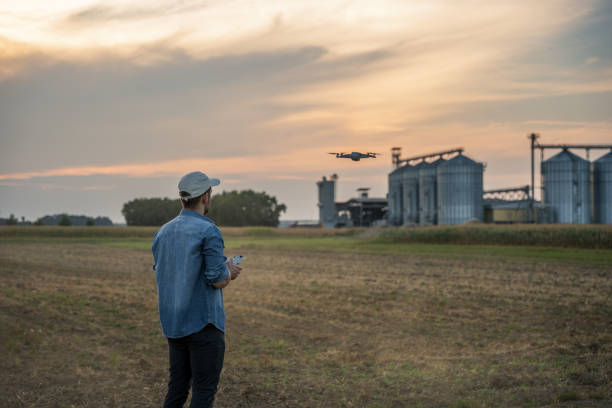 Male farmer with remote controller flying drone above farmland