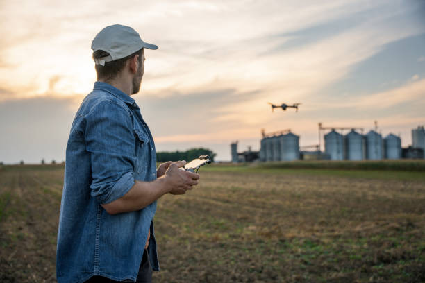 istock Male farmer with remote controller flying drone above farmland 1451087407
