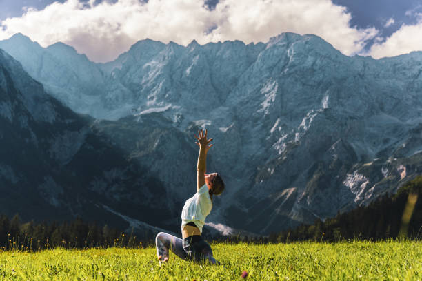istock Woman practicing crescent moon pose on grassy against majestic mountain 1451089070