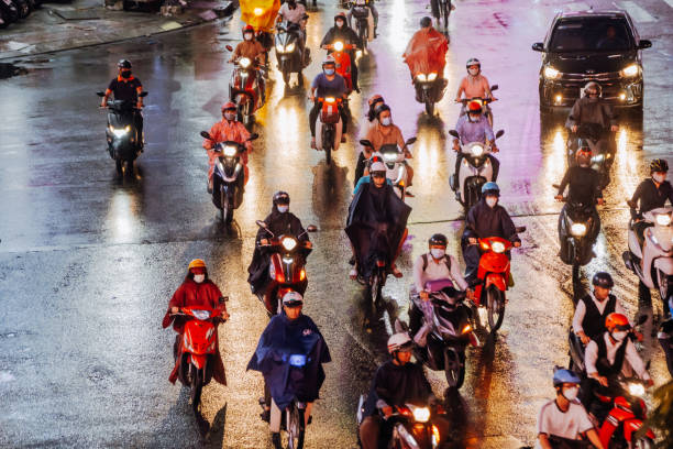 Vietnamese people on motorcycles evacuate from flooded streets through puddles in Nha Trang after flooding in heavy rain in Asia. Nha Trang, Vietnam - November 21, 2025