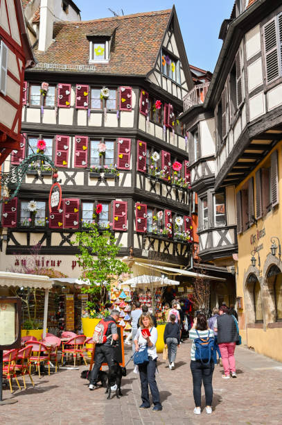 Colmar, France - April 2022: People in one of the narrow streets of old decorated buildings in the centre of Colmar
