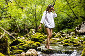 Carefree woman walking on rocks amidst flowing river