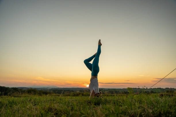 istock Woman practicing garuda salamba sirsasana on grassy landscape 1451091082