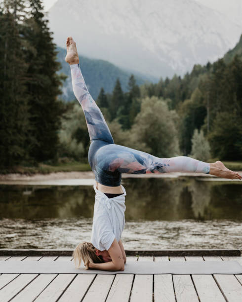 istock Female yogi practicing headstand and doing splits on pier by lake 1451091838