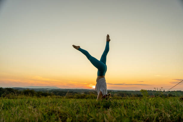 istock Female yogi practicing headstand on grassy landscape during sunrise 1451091843