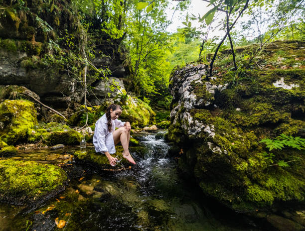 istock Woman pouring water in flowing river at rainforest 1451091881