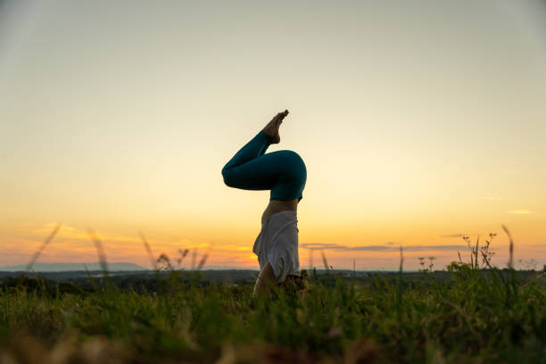 istock Woman practicing garuda salamba sirsasana on grassy landscape 1451091925