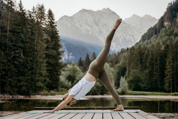 istock Female yogi with leg up practicing downward facing dog position on pier 1451092365