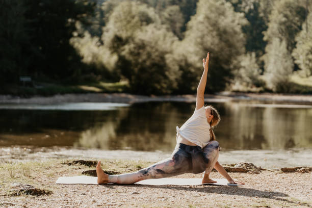 istock Rear view of woman practicing extended side angle pose at lakeshore 1451092681