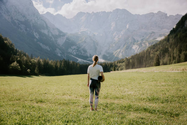 Rear view of woman with exercise mat looking at mountains