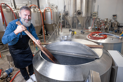 Stirring beer. Brewery worker stirring fresh beer in a tank