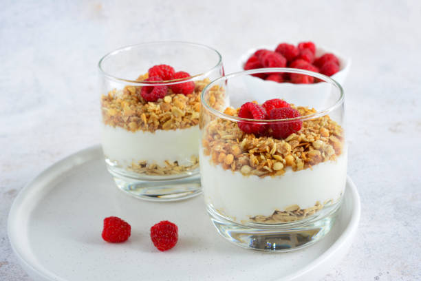 istock granola with greek yogurt and garden raspberry in drinking glasses on white background 1451095668