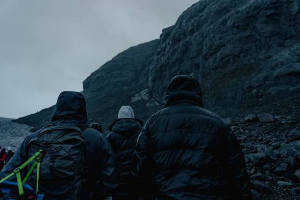 istock Group of hikers in black jackets climbing the cliff. 1451096259