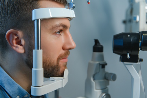 Handsome young man is checking the eye vision in modern ophthalmology clinic. Patient in ophthalmology clinic.