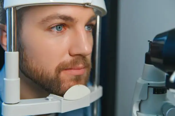Adult man eyesight test with binocular slit-lamp. Checking retina of a male eye close-up. Ophthalmology Clinic.