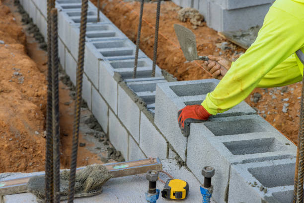 Bricklayer construction worker putting down another row of cement blocks stock photo