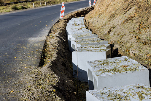 Installing precast u-shape concrete drains along reconstruction road for purpose of draining ground