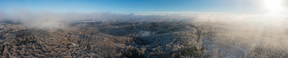 Panoramic aerial view of a forest area covered with hoarfrost and wafts of fog in the Taunus/Germany
