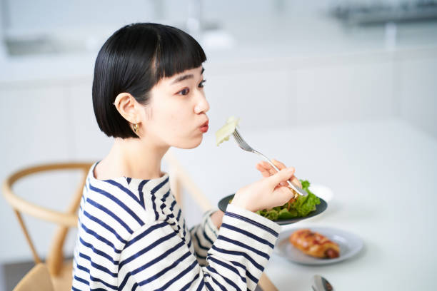 mujer comiendo en casa cenando - tasting women eating expressing positivity fotografías e imágenes de stock