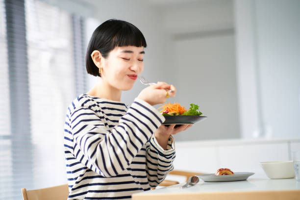 家で食事をする女性 - tasting women eating expressing positivity ストックフォトと画像