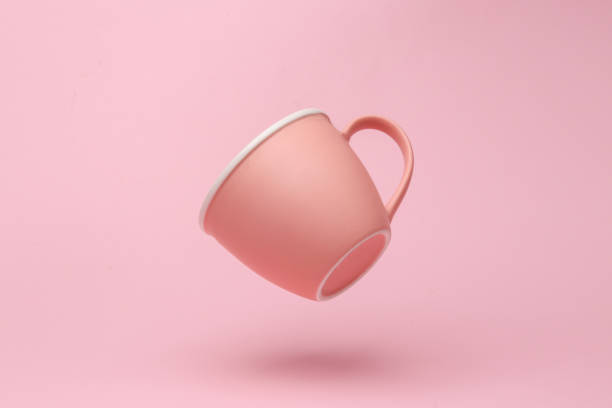 istock Pink ceramic cup flying in antigravity on pink background with shadow. Levitation object in the air. Creative minimal layout 1451104025