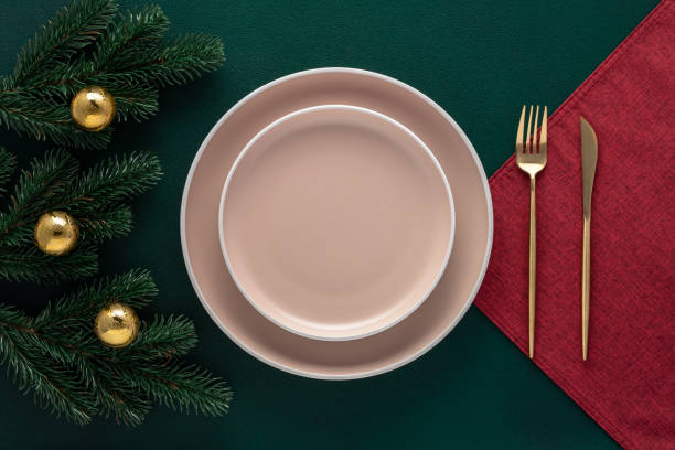 istock Christmas table setting with New Year decorations. Empty plates and golden cutlery on a dark green. Crockery. Top view. Dining, festive decor in a luxury restaurant. Card or menu template, flat lay. 1451104030