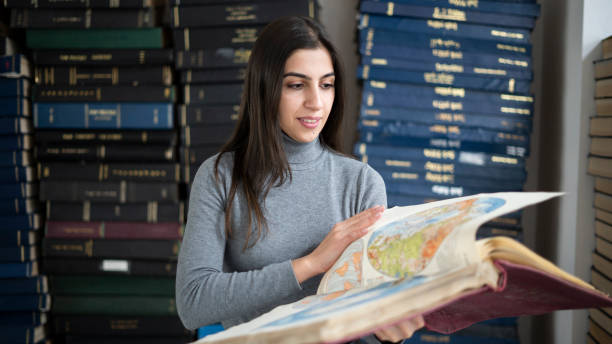 istock Beautiful woman examining books in university library 1451106176