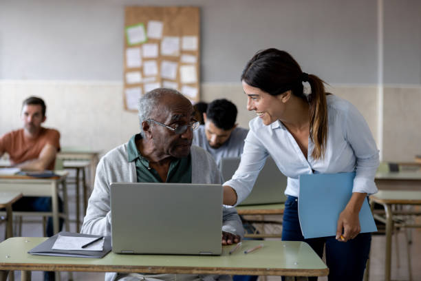 Teacher assisting a senior adult taking a computer class