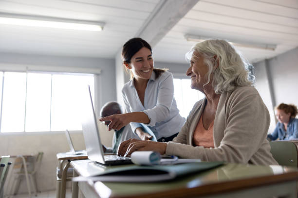 istock Happy teacher helping a senior student while using a laptop in her class 1451106857