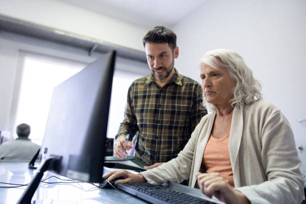 istock Teacher helping a senior woman taking a computer class 1451106890