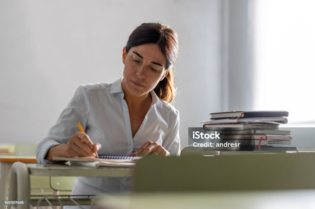 Adult woman going back to school and writing in her notebook Latin American adult woman going back to school and writing in her notebook - education concepts Teacher Stock Photo