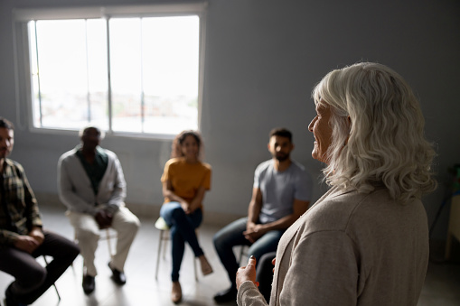 Mental health professional talking in a group therapy session - healthcare and medicine concepts