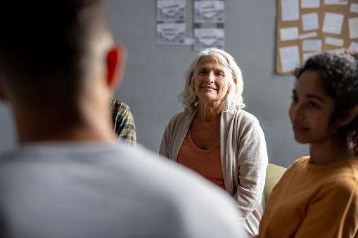 Latin American senior woman listening to a man talking at a group therapy session - mental health concepts