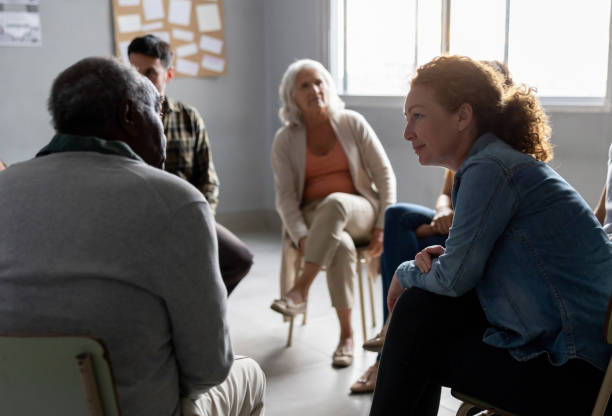 persone che condividono storie in una sessione di terapia di gruppo - senior adult group therapy social gathering community center foto e immagini stock