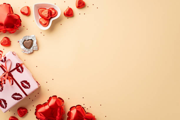 valentine's day concept. top view photo of giftbox in wrapping paper with kiss lips pattern heart shaped balloons plate with candies and sequins on isolated pastel beige background with empty space - valentines day candy chocolate candy heart shape imagens e fotografias de stock