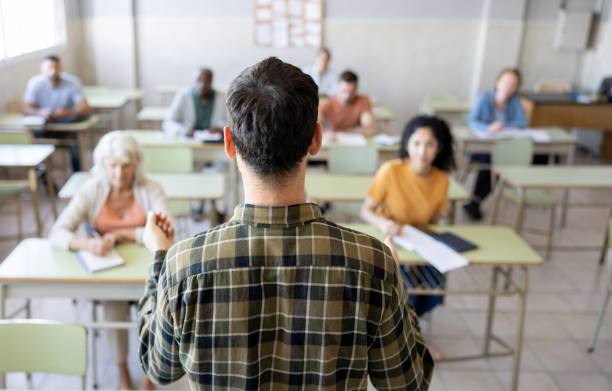 istock Rear view of a university teacher teaching a class to a group of students 1451108308