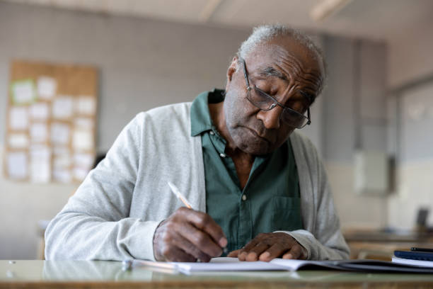 senior man studying in college and writing on his notebook in the classroom - night school imagens e fotografias de stock