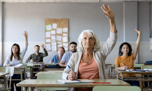 Latin American adult student raising her hand to ask a question in class - education concepts