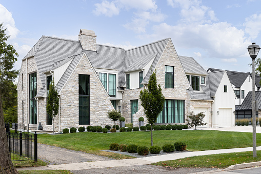 Barrington, IL, USA - October 5, 2021: A luxury modern farmhouse home with a stone and vertical board and batten siding, large windows, and beautiful landscaping.