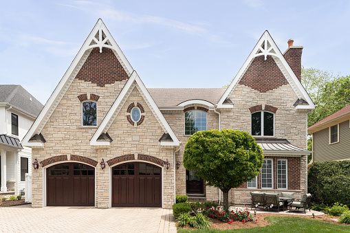 Oak Park, IL, USA - May 23, 2021: A full masonry home with a two car garage, front yard patio, brick paver driveway, and a mixture of brick and stone throughout the exterior.