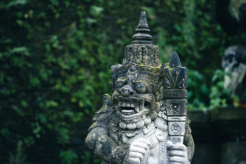 Traditional demon sculpture made of stone in the jungle of the Bali island, Indonesia.