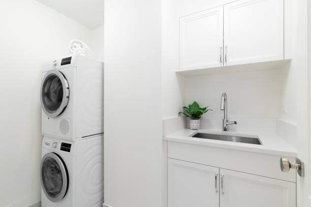 A laundry room with a sink, cabinets, and appliances.