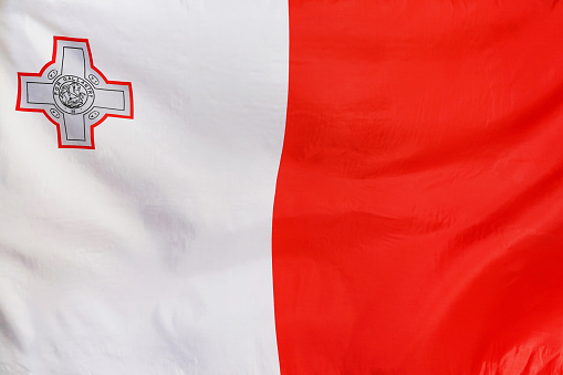 Fabric texture flag of Malta. Flag of Malta waving in the wind. Flag of Malta is depicted on a sports cloth fabric with many folds. Sport team banner
