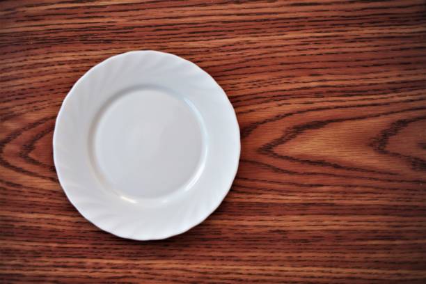 istock White dining plate on the table with a brown wooden pattern 1451114875