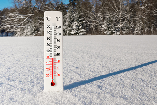 White celsius and fahrenheit scale thermometer in snow. Ambient temperature zero degrees celsius