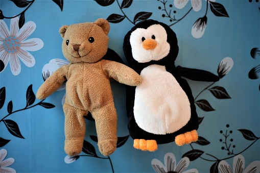 plush toys brown bear and penguin on a blue colorful background