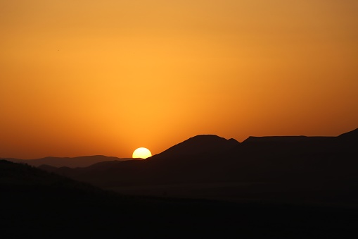 De colinas con una puesta de sol naranja en el fondo photo