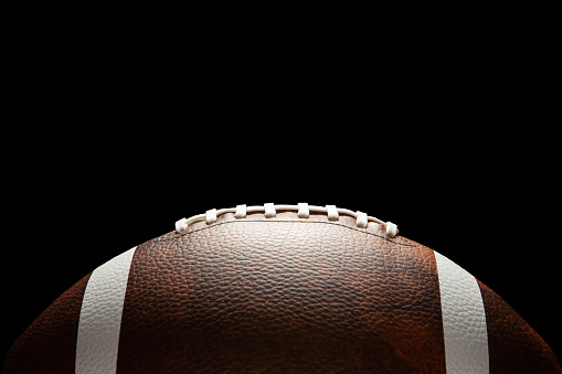 American football ball on dark background with space for text.