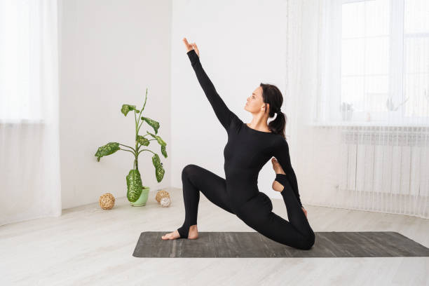 Woman leading a healthy lifestyle and practicing yoga, performs a variation of the anjaneyasana exercise with virasana, a pose with a low lunge, trains in sportswear while sitting on a mat in the room mujer que lleva un estilo de vida saludable y practica yoga, realiza una variación del ejercicio anjaneyasana con virasana, una pose con una estocada baja, entrena en ropa deportiva mientras está sentada en una colchoneta en la habitación